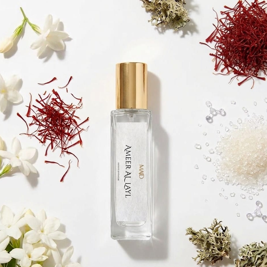 Perfume bottle with gold cap on a white background surrounded by flowers and herbs