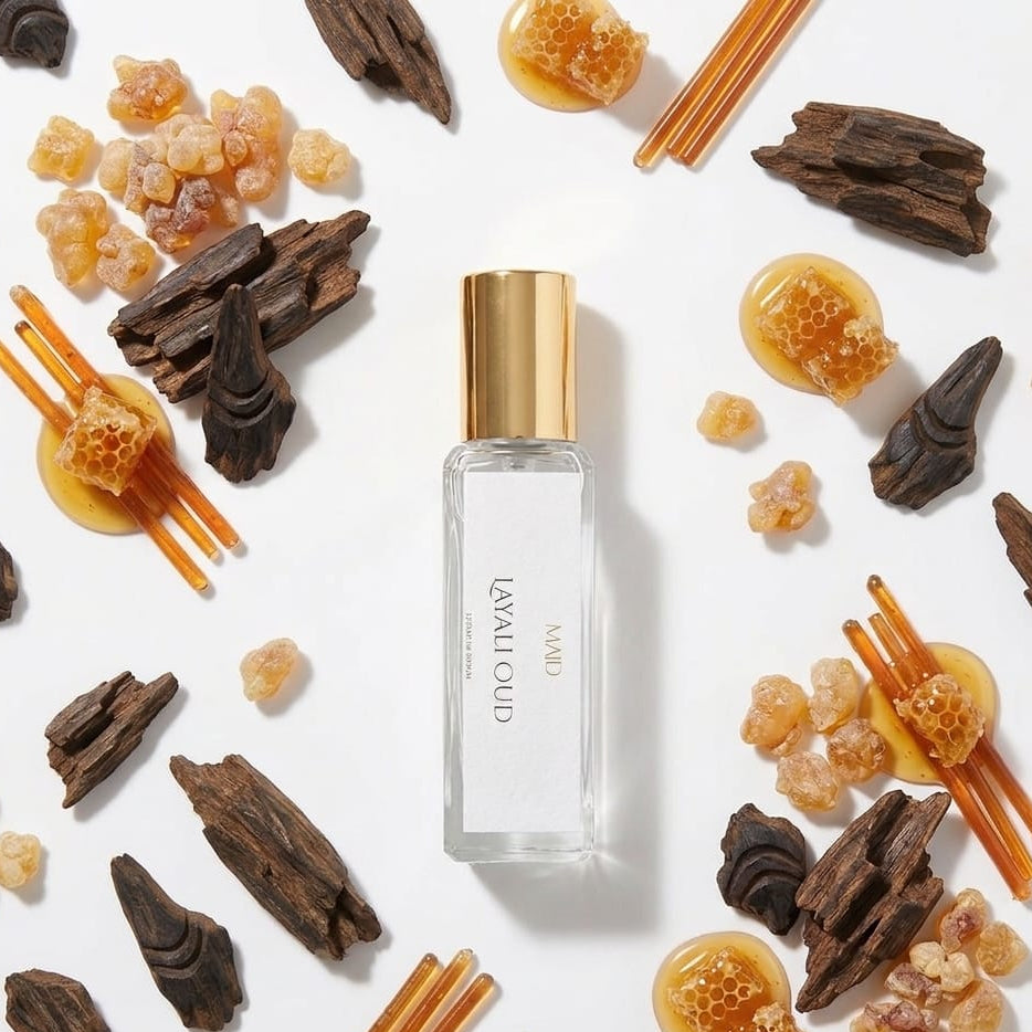 Perfume bottle with gold cap surrounded by dried herbs and spices on a white background